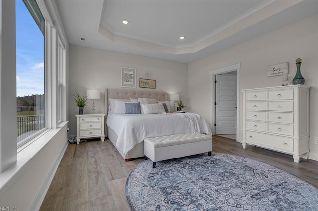 bedroom featuring a tray ceiling, wood finished floors, and baseboards