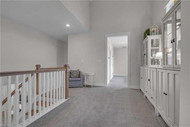 hall featuring carpet floors, a high ceiling, and baseboards