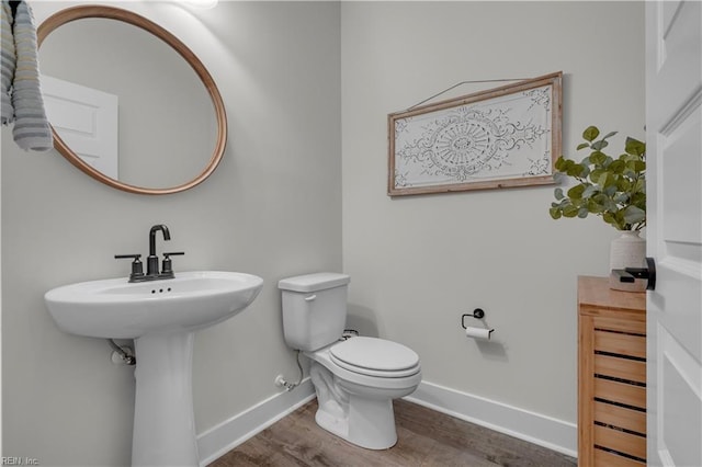 half bath featuring toilet, baseboards, and wood finished floors