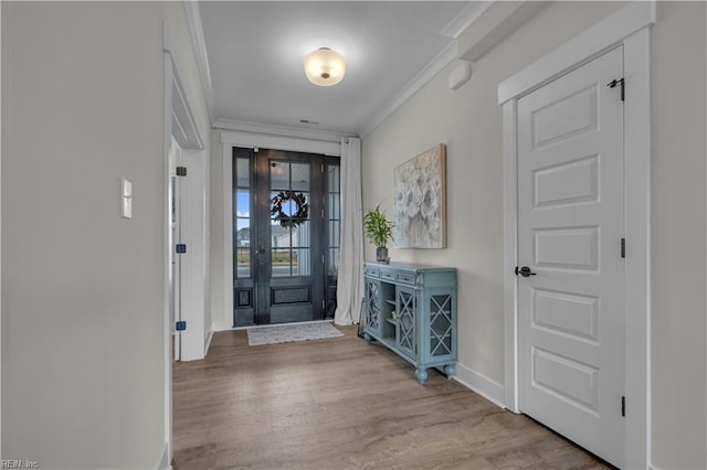 foyer entrance with baseboards, crown molding, and wood finished floors