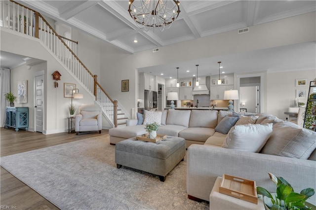 living room with a high ceiling, wood finished floors, visible vents, stairway, and crown molding