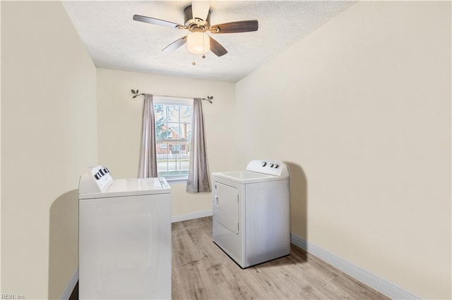 clothes washing area featuring light wood-type flooring, laundry area, washer and clothes dryer, and a textured ceiling