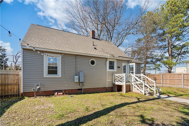 back of property featuring a chimney, fence, a lawn, and roof with shingles