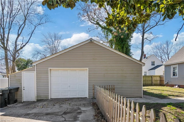 detached garage with fence and concrete driveway