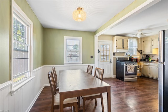 dining room with a wainscoted wall, dark wood-type flooring, and a wealth of natural light