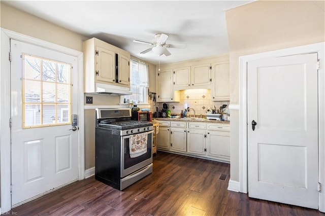 kitchen with tasteful backsplash, dark wood-style flooring, stainless steel gas range, light countertops, and under cabinet range hood