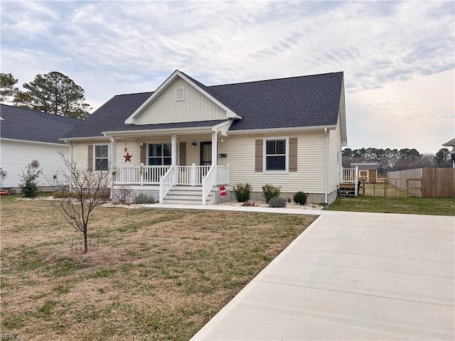 view of front facade featuring covered porch, fence, and a front yard