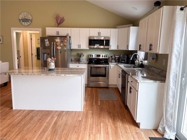 kitchen with light stone counters, light wood-style flooring, a sink, white cabinets, and appliances with stainless steel finishes