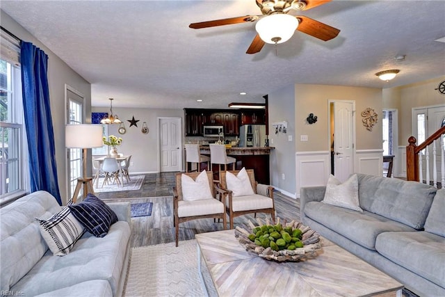 living area featuring a textured ceiling, stairway, dark wood-type flooring, and wainscoting