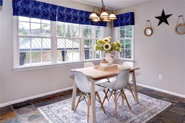 dining space featuring stone tile floors, baseboards, and a notable chandelier