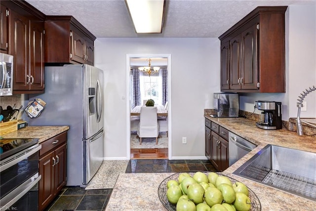 kitchen with a textured ceiling, stainless steel appliances, light countertops, and a chandelier