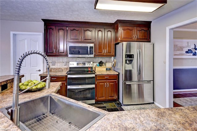 kitchen with a sink, stainless steel appliances, a textured ceiling, light countertops, and backsplash