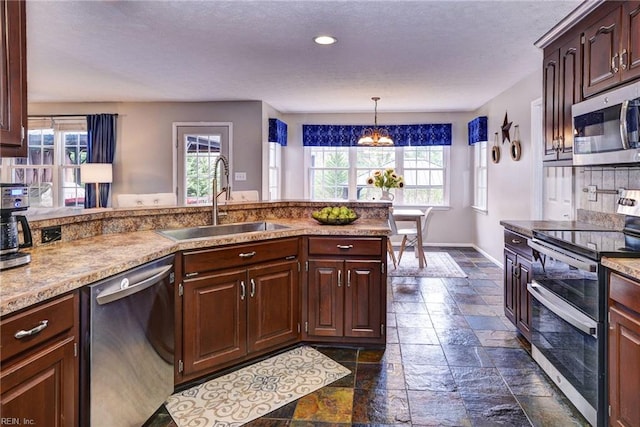 kitchen with stone tile floors, stainless steel appliances, tasteful backsplash, a sink, and baseboards