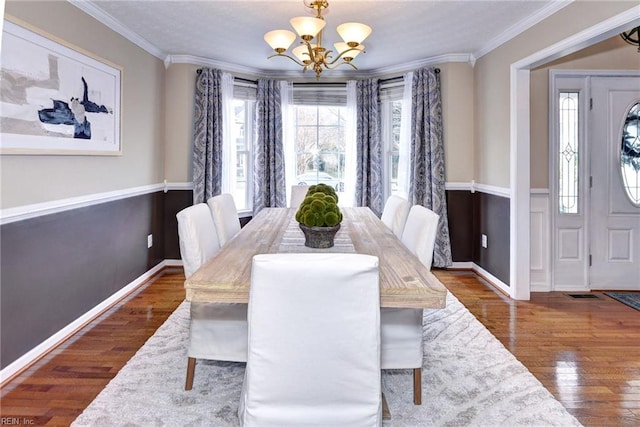 dining room featuring ornamental molding, a notable chandelier, baseboards, and wood finished floors