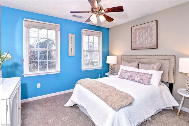 carpeted bedroom featuring multiple windows, baseboards, and a ceiling fan