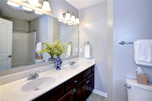 full bath featuring baseboards, a sink, toilet, and double vanity