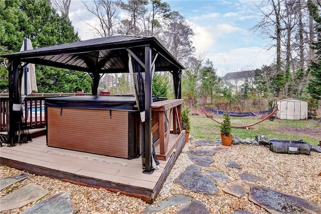 wooden deck with an outbuilding, a hot tub, a gazebo, and a shed