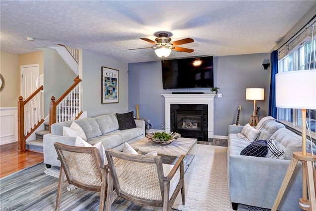 living room with a fireplace with flush hearth, a textured ceiling, stairway, and wood finished floors