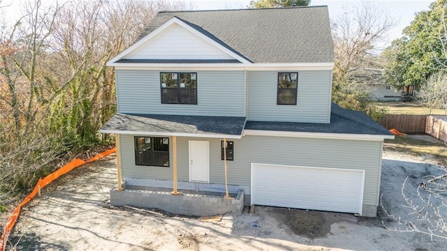 view of front of house with fence, driveway, covered porch, a shingled roof, and a garage