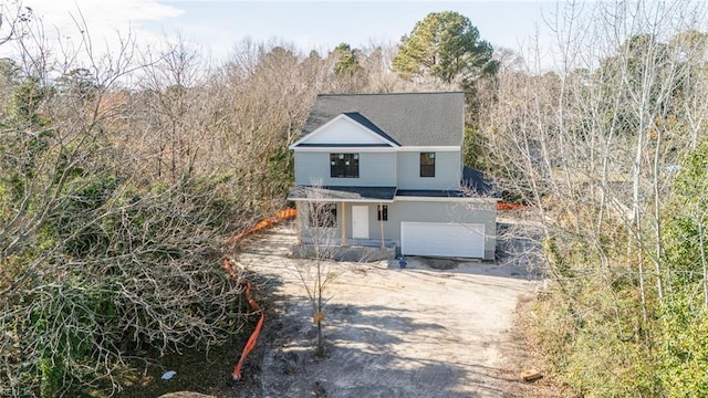 view of front of property with a wooded view, a garage, and driveway