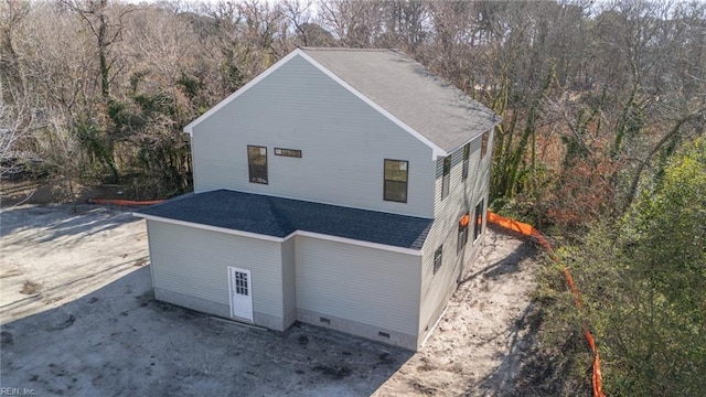 view of side of home featuring crawl space, a view of trees, and a shingled roof