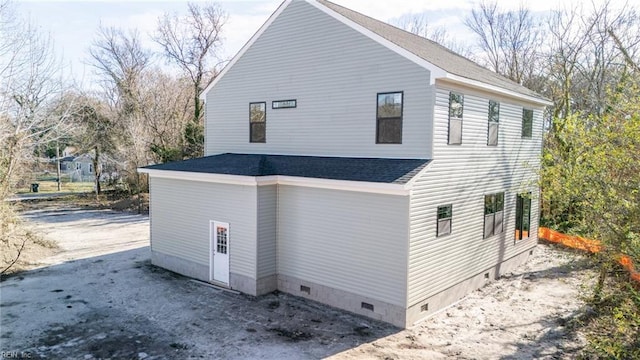 view of side of property with crawl space and a shingled roof