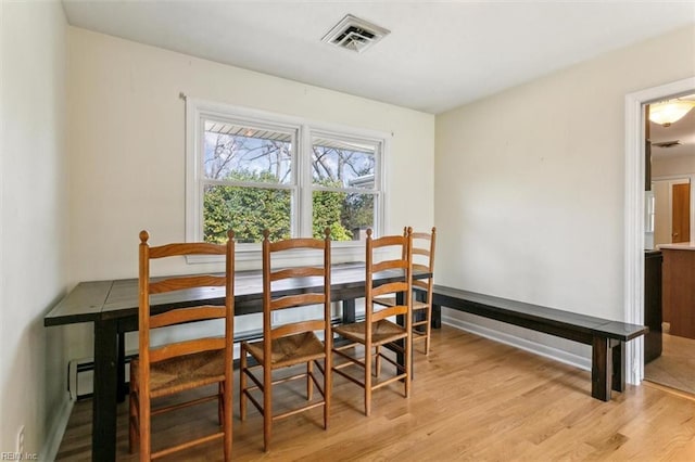 dining area with light wood-type flooring and visible vents