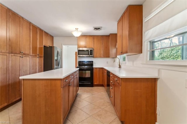 kitchen featuring visible vents, brown cabinets, a center island, black appliances, and a sink