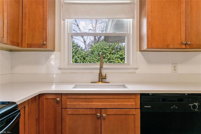 kitchen featuring black dishwasher, brown cabinets, light countertops, a sink, and range with electric stovetop