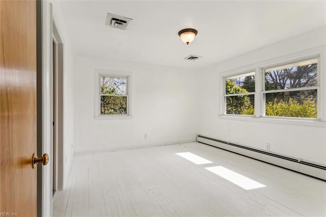 empty room with plenty of natural light, a baseboard radiator, and visible vents