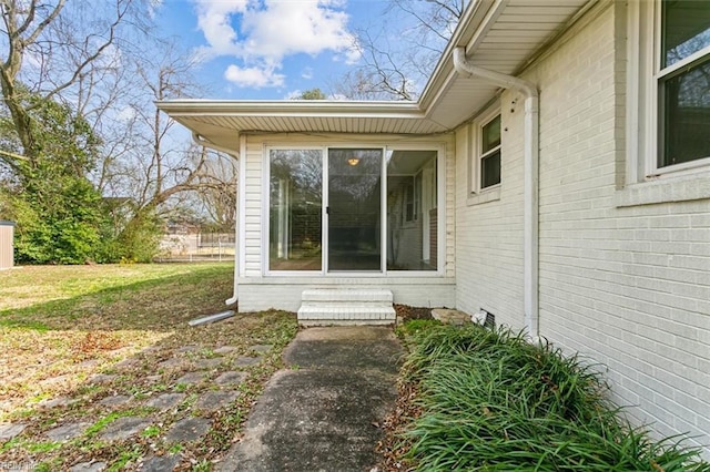 view of side of home featuring entry steps, a yard, and brick siding