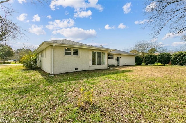 rear view of house featuring crawl space, brick siding, and a lawn