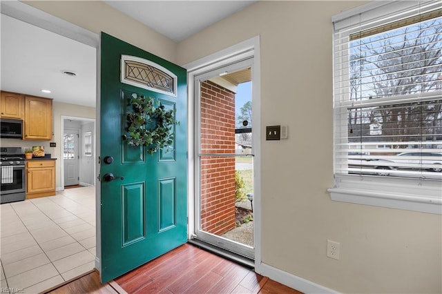 entrance foyer with light wood-style floors, a healthy amount of sunlight, visible vents, and baseboards