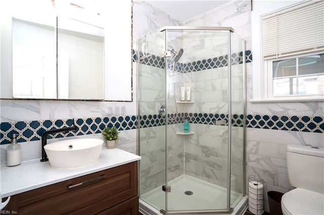 full bath with toilet, a shower stall, tile walls, and vanity