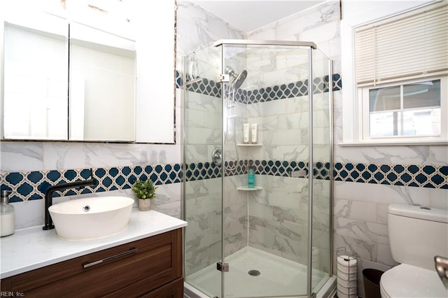 bathroom with tile walls, toilet, a shower stall, and vanity