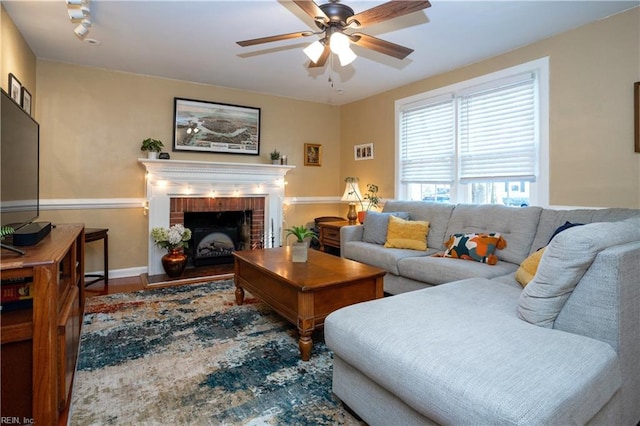 living area featuring a fireplace, wood finished floors, and a ceiling fan