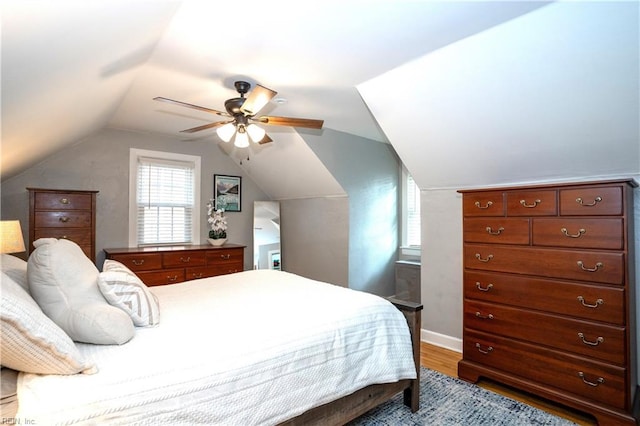 bedroom with lofted ceiling, baseboards, a ceiling fan, and wood finished floors