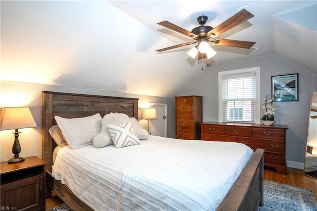 bedroom with dark wood-style flooring, vaulted ceiling, baseboards, and ceiling fan