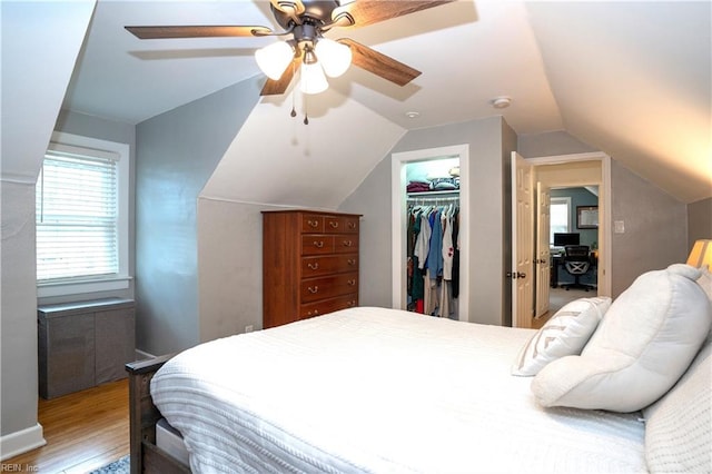 bedroom featuring a ceiling fan, light wood-style flooring, a spacious closet, vaulted ceiling, and a closet