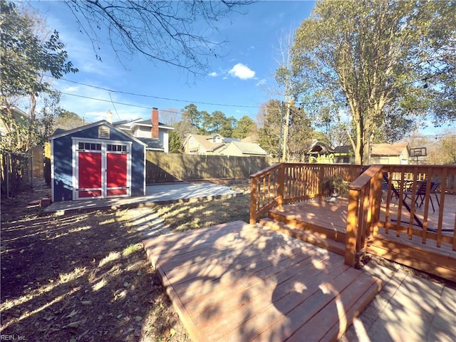 deck featuring a storage shed, an outbuilding, and a fenced backyard