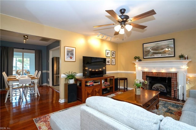 living room with a fireplace, visible vents, ceiling fan, wood finished floors, and baseboards