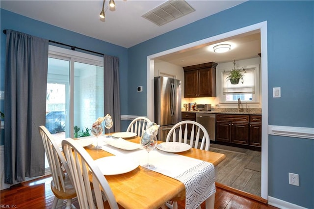 dining area featuring dark wood-type flooring, visible vents, and baseboards