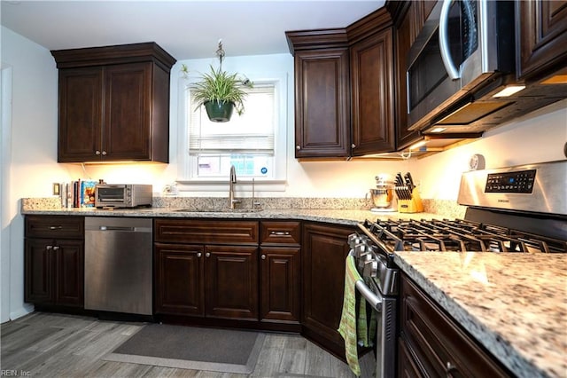 kitchen featuring appliances with stainless steel finishes, a toaster, a sink, and dark brown cabinetry