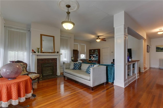 living room with ceiling fan, radiator heating unit, wood finished floors, and ornate columns