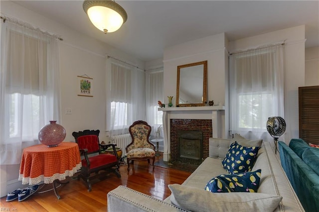 living area with radiator, a fireplace, and wood finished floors