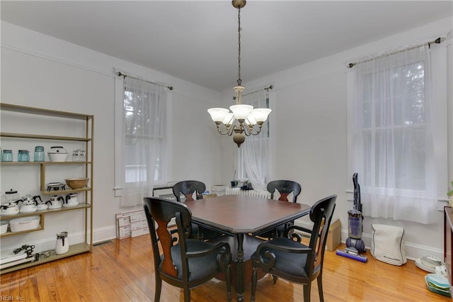 dining room featuring light wood-type flooring, baseboards, and an inviting chandelier