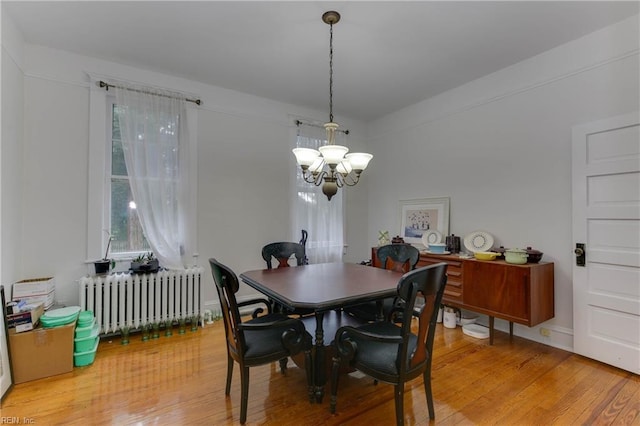 dining area featuring radiator, light wood-type flooring, and a chandelier