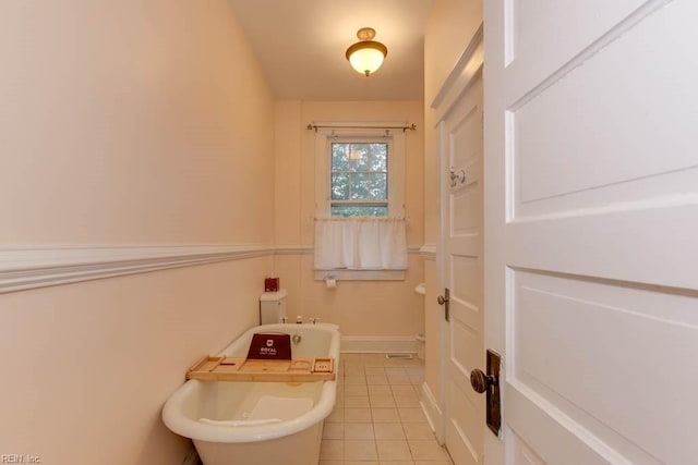 bathroom featuring a soaking tub, tile patterned flooring, and baseboards