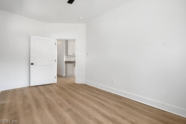 unfurnished bedroom with a ceiling fan, wood finished floors, and baseboards