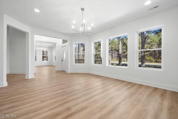 interior space featuring a notable chandelier, light wood-style floors, visible vents, and baseboards